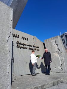 Kaksi henkilöä laskee kukkia muistomerkille.