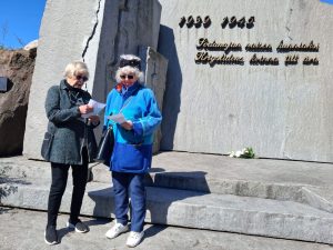 Kaksi henkilöä muistomerkin edessä.