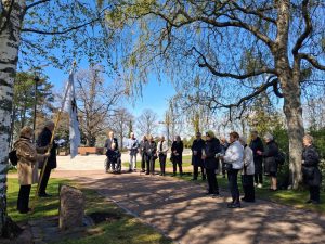 Ryhmä henkilöitä hartaustilaisuudessa muistelukivellä.